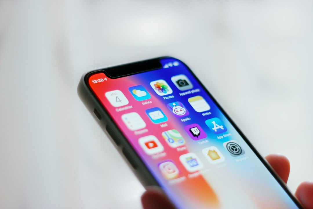 Mão segurando um smartphone com a tela inicial de aplicativos
